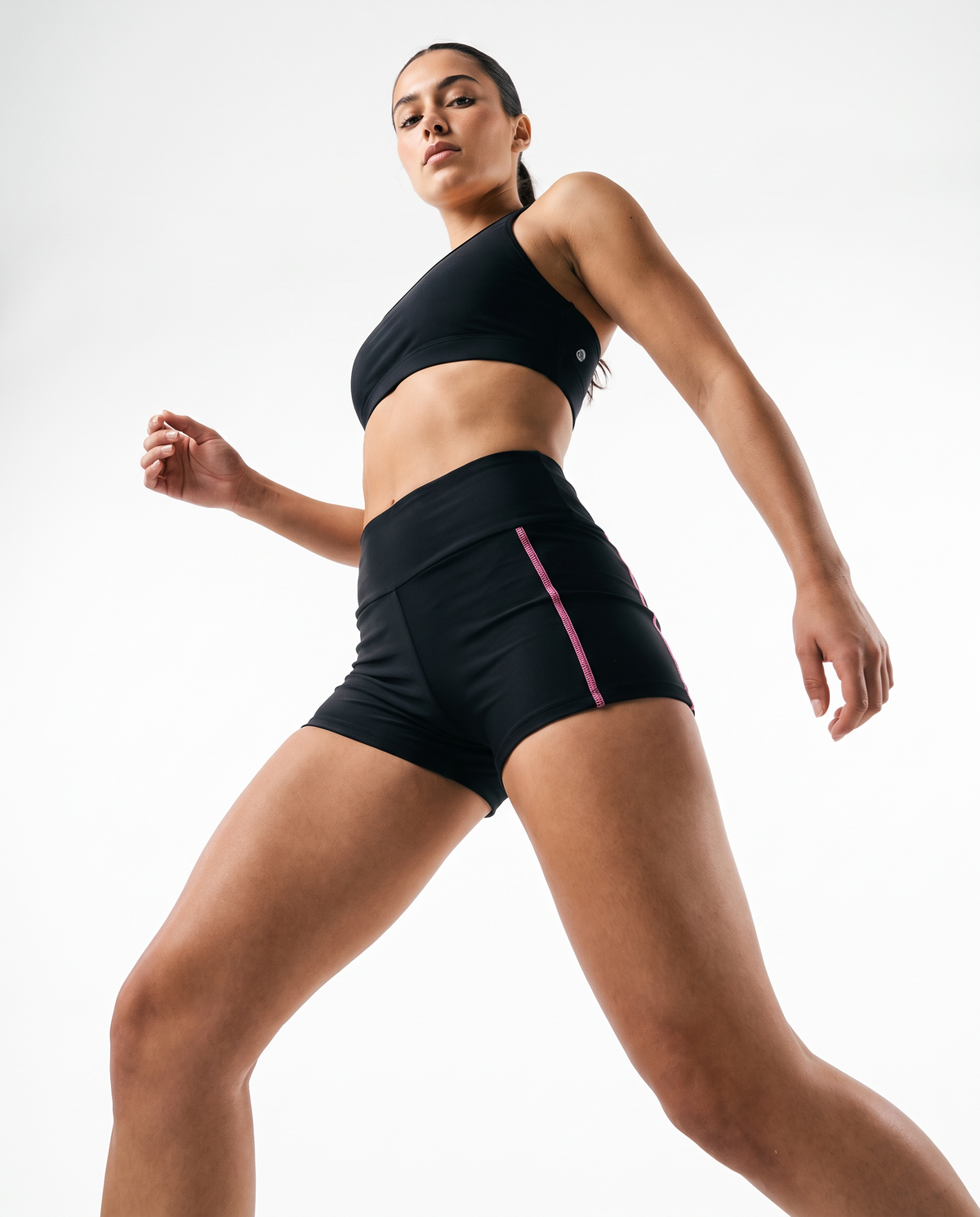 A high-end commercial product photograph of a young model in a dynamic, confident pose, captured from a dramatic angle shot to emphasize the product.  Studio lighting with white background. Shot on a 35mm lens, f/2.8, sharp focus on the product details, hyper-realistic textures, professional color grading with clean, modern tones, 8k resolution, no shadows @Women's High Waisted Yoga Biker Shorts